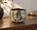 AI-generated setting : Blue grey chawan with ochre runs, on a walnut console.