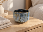 Ambientazione creata con IA : Chawan azzurro tenue con colature ocra, su un comò con anelli.