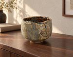 AI-generated setting : Grey blue chawan with ochre patches, on a walnut console.