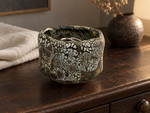 Ambientazione creata con IA : Chawan nero bruno con isole crema, su un comò con anelli.