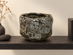 Ambientazione creata con IA : Chawan nero bruno con isole crema, su una mensola.