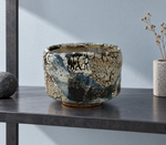 Ambientazione creata con IA : Chawan blu scuro con zone crema, su una mensola.