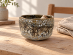 Ambientazione creata con IA : Chawan bruno con segni chiari, su un tavolo con accessori da cucito.