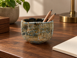 Ambientazione creata con IA : Chawan blu grigio e ocra, su una scrivania con piccoli oggetti.