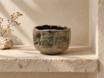 Ambientazione creata con IA : Chawan blu grigio e ocra, in una nicchia.