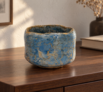 AI-generated setting : Blue chawan with a golden toned network, on a walnut console.