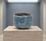 AI-generated setting : Blue chawan with a golden toned network, on a travertine plinth.